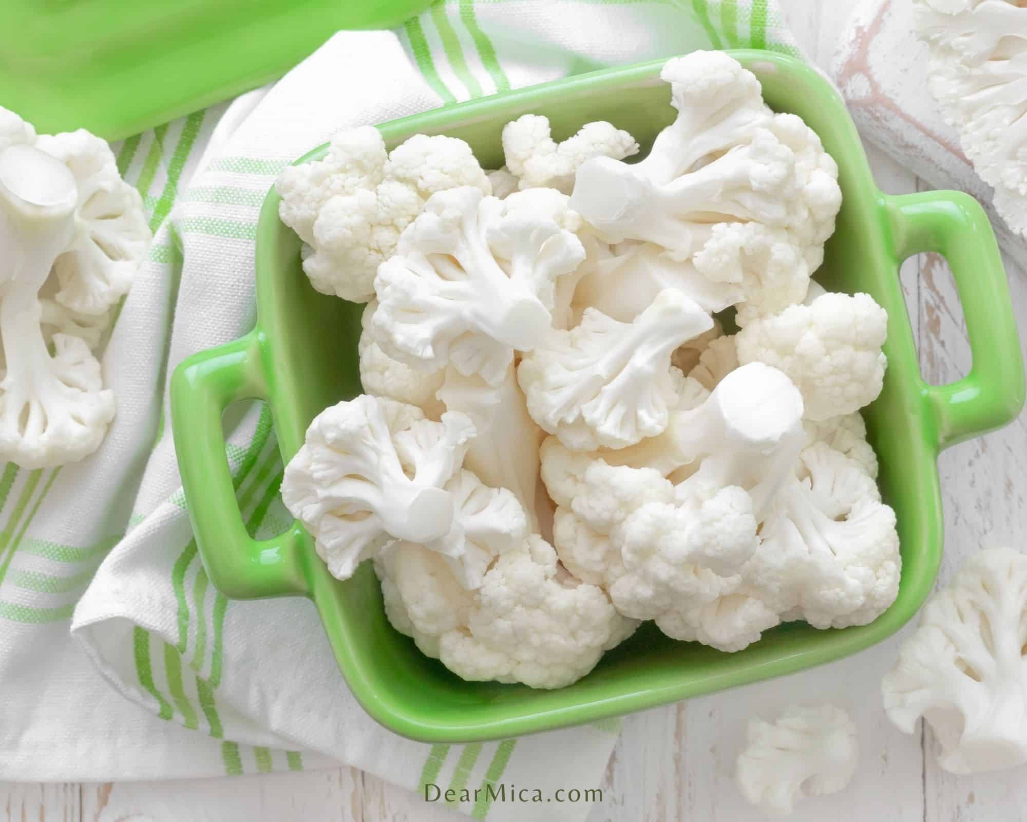 top view of cauliflower florets in a green ceramic container
