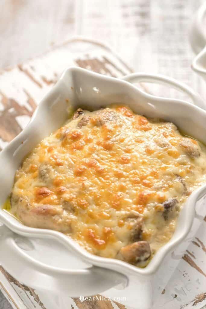 Top view of a keto chicken cheese bake served on a small individual baking dish on a white wood table.
