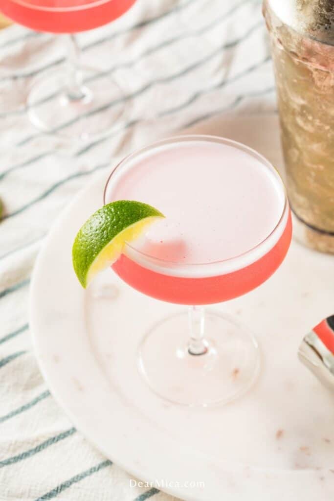 A top view of a pink keto cosmopolitan cocktail garnished with lime wedge.