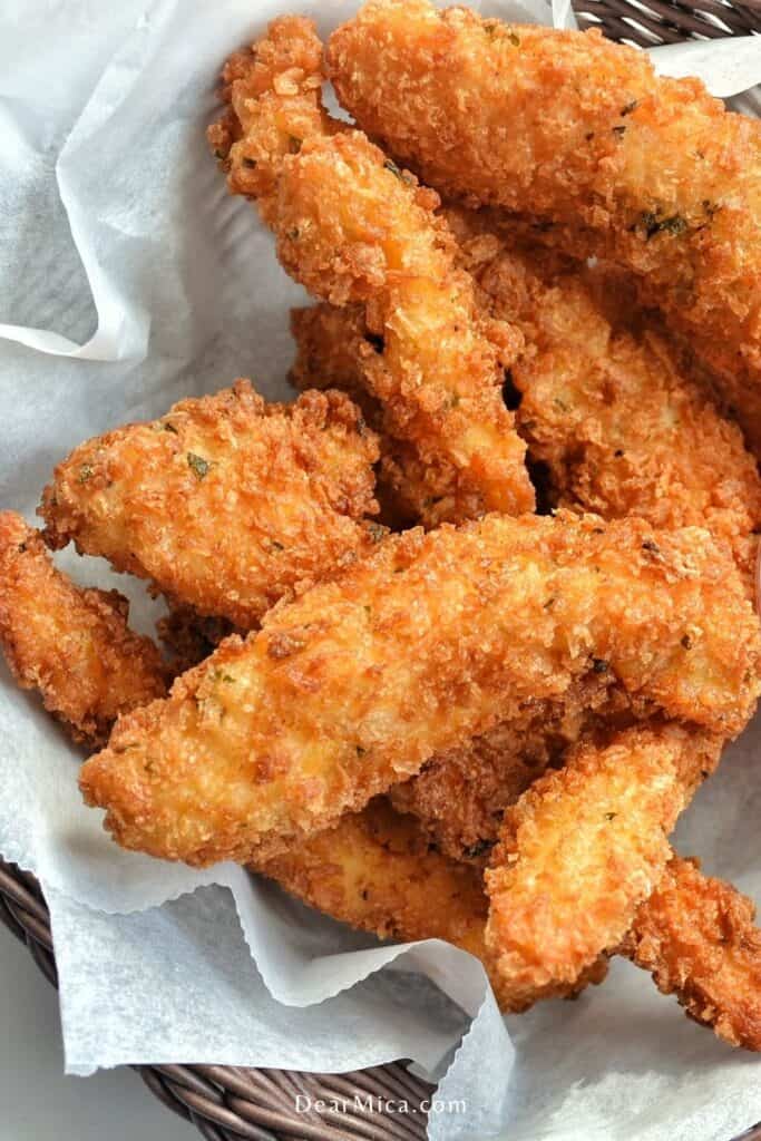 Top view of Keto Coconut Chicken Tenders served on a basket lined with parchment paper.