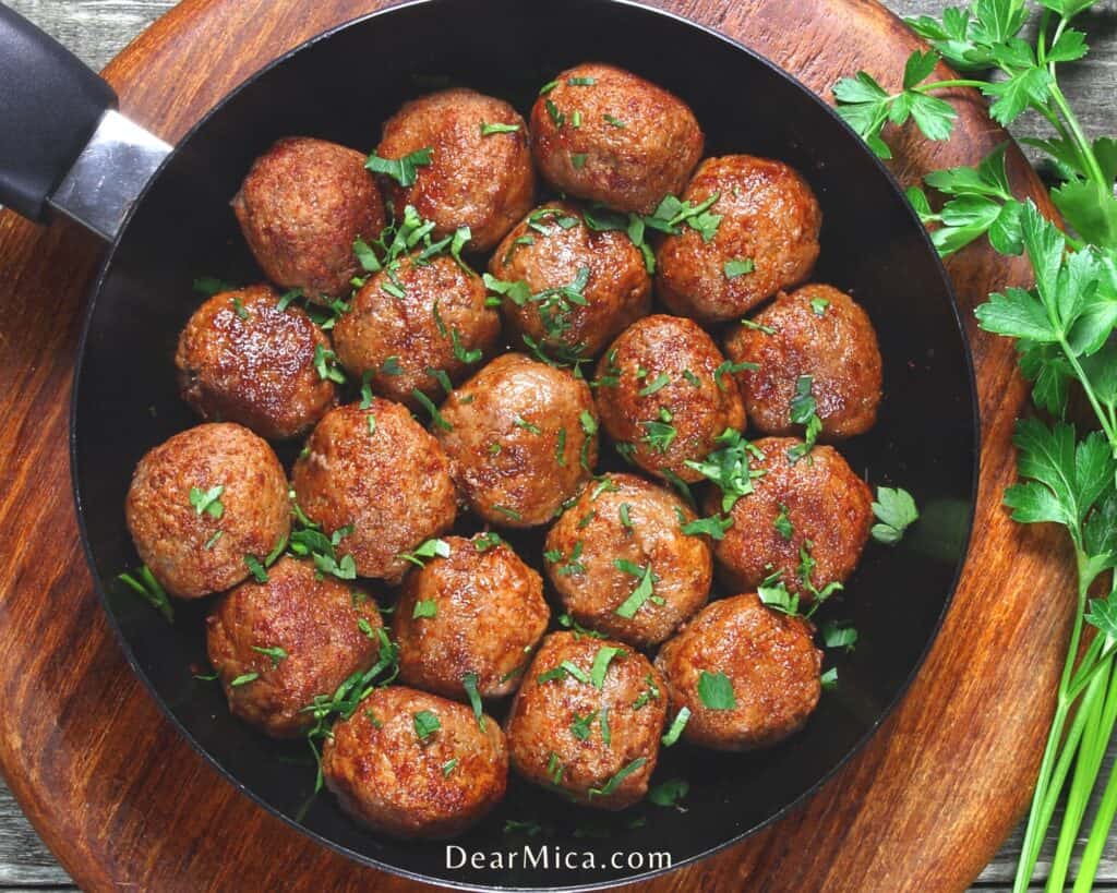 Top view of keto sausage balls in a pan on a wooden background.