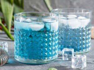 Side view of two Keto Blue Lagoon Cocktails on a gray background.