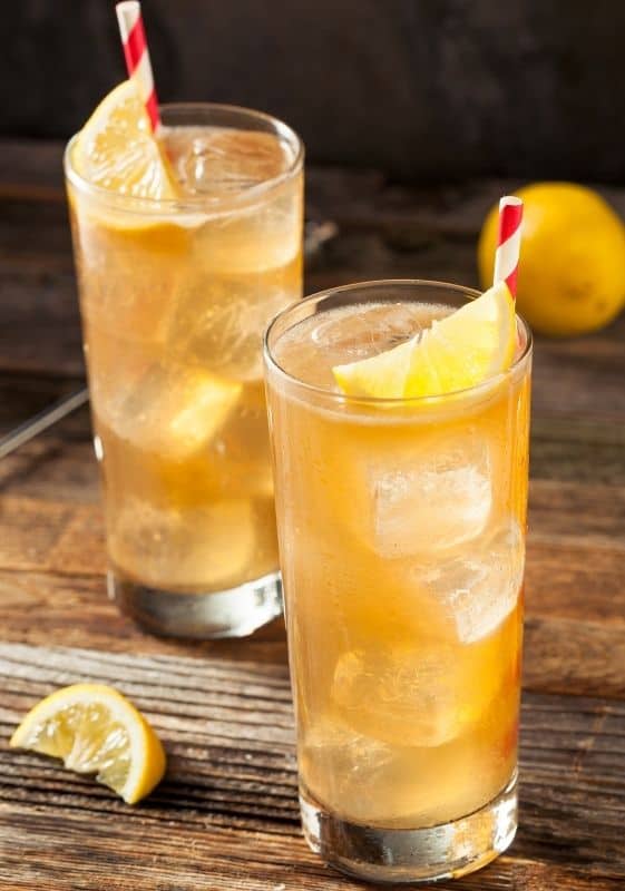 Top view of two Keto Long Island Iced Tea in tall skinny glassed garnished with lemon wedge on a wooden table.