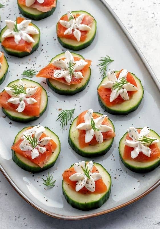 Top view of low carb smoked salmon cucumber bites on a serving platter garnished with dill.