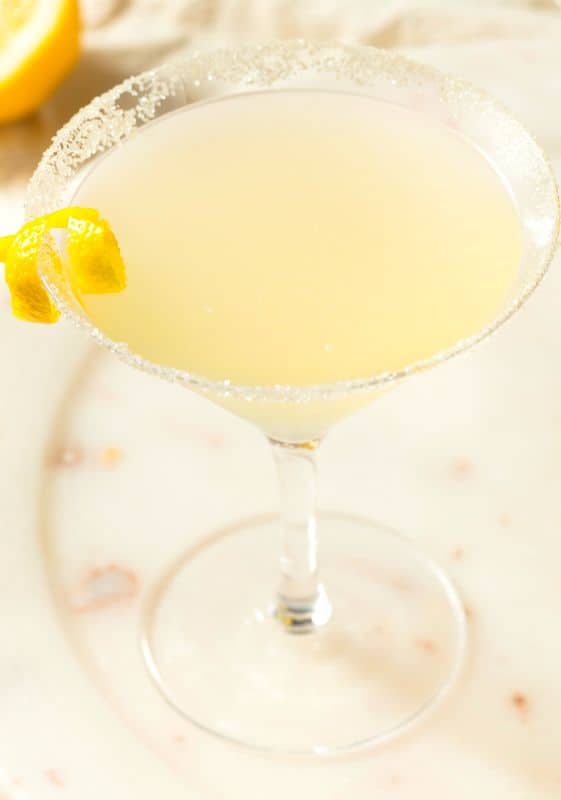 Closeup view of a keto lemon drop martini cocktail garnished with lemon skin ribbons.