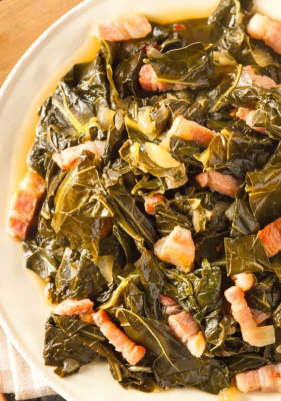 Closeup view of keto collard greens with bacon served on a white plate.