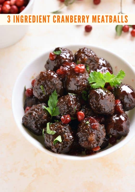 A 3 ingredient cranberry meatballs in a white bowl garnished with parsley.