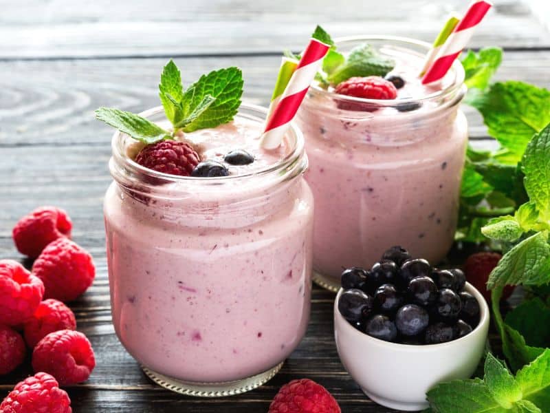 Keto smoothie recipes featuring raspberry smoothie in a jar garnished with fresh berries and mint leaves.